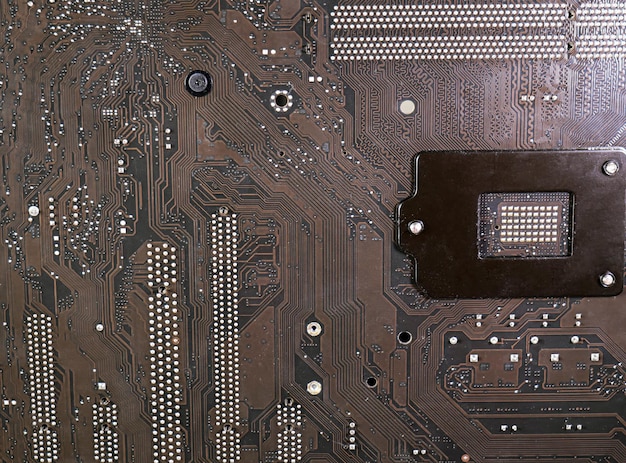 The surface of the motherboard dark brown has a pattern of data paths and the current has a point caused by lead solder It's the circuit board under the CPU