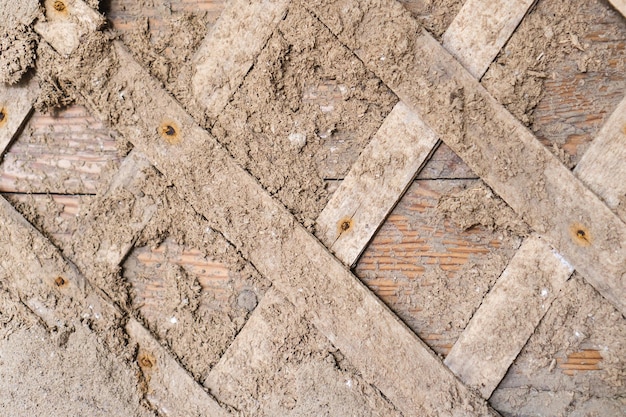 Surface of old wooden wall covered with clay plaster mixture with planks Closeup