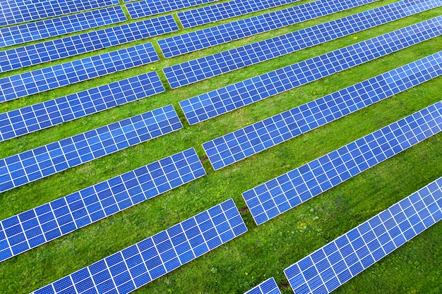 Surface of solar photo voltaic panels system producing renewable clean energy on green grass background