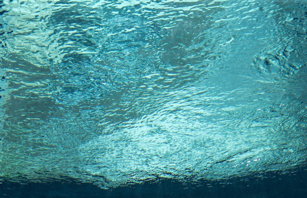 Surface of a swimming pool taken underwater with waves