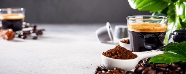 surface with glass cup of coffee, coffee beans and leafs. Beverage cafe shop concept with copy space