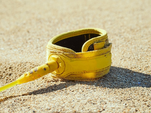 Surfboard leash on beach. Close-up of surfboard leash on beach in the sunshine.