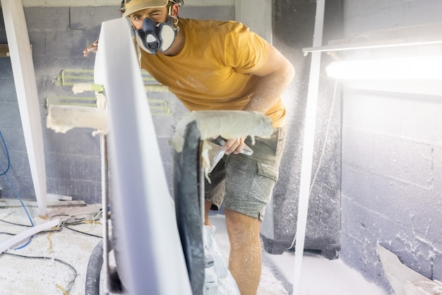 Photo surfboard shaper workshop man checking quality of surfboard work