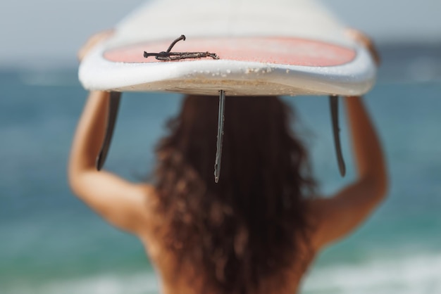 Foto surfboard over surf girl di fronte al mare durante le vacanze estive in spiaggia