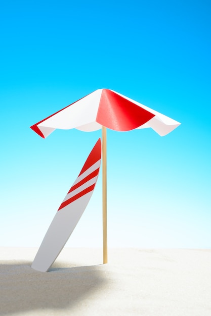 Surfboard under an umbrella on the sandy beach