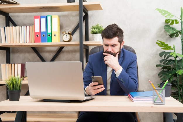 Surfen op internet Man bebaarde baas manager zit kantoor met laptop Manager die zakelijke problemen oplost Zakenman die de leiding heeft over succesvolle zakelijke oplossingen Ontwikkeling van bedrijfsstrategie Risicovolle onderneming