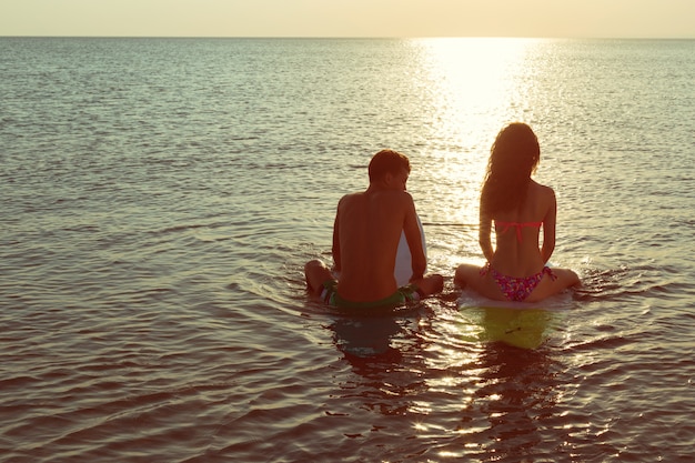 Surfen paar leunend op surfplanken in zee