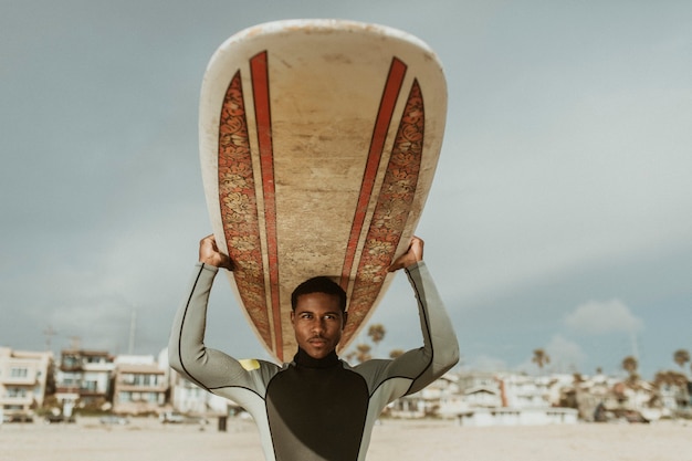 Surfista che porta una tavola da surf in spiaggia