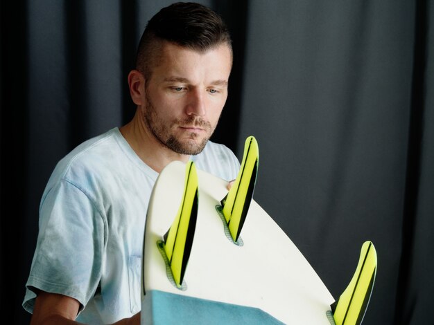 Surfer checks surfboard at home.