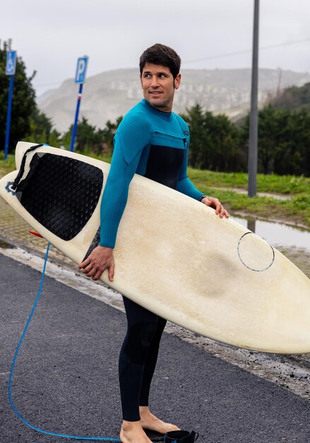 Surfer die met een surfplank naar het strand loopt verticale foto