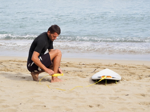 Surfer draagt een gele surfplank op het strand