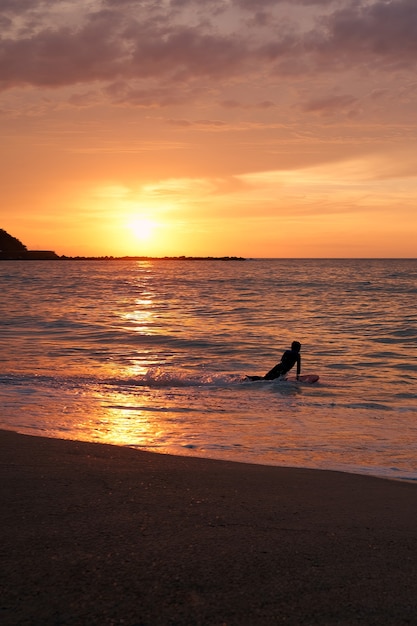 Surfer getting on his board at sunset