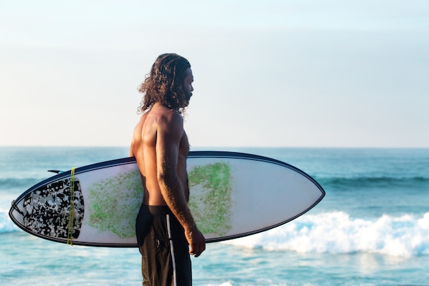 Surfer holding a surfboard by the ocean shore