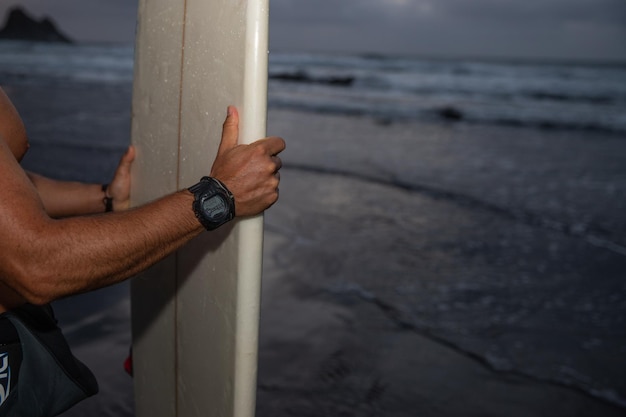 Surfer holds up a surfboard at the beach photo with copy space on the right