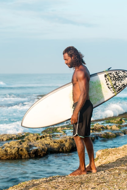 Surfer houdt een surfplank vast op de kust van de Indische Oceaan