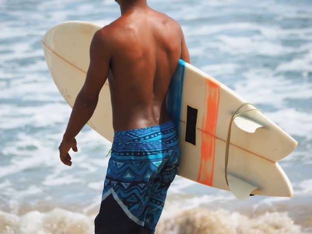 Surfer in korte broek maakt zich klaar om de oceaan in te gaan