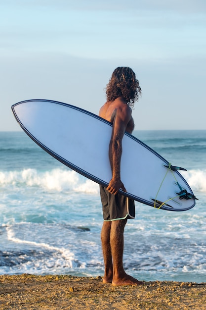 The surfer is holding a surfboard on the Indian Ocean shore