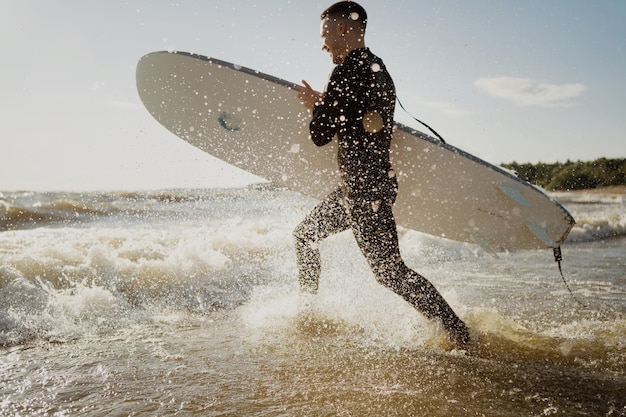 Surfer man in a wetsuit surfing in the sea on a sunny day at\
sunset