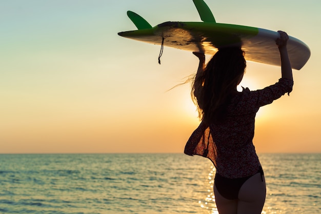 Surfer meisje surfen kijken naar oceaan strand zonsondergang