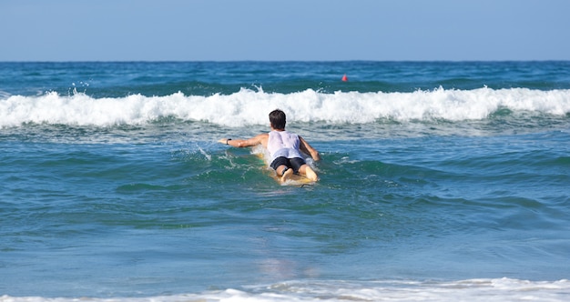 Surfer op longboard berijdt een golf in de zee