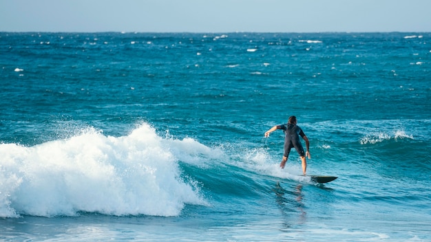 Surfer riding wave in daylight long view