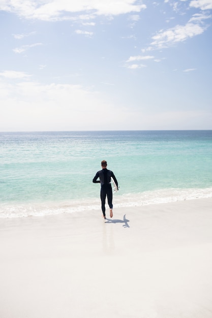 Surfer running towards sea with a surfboard