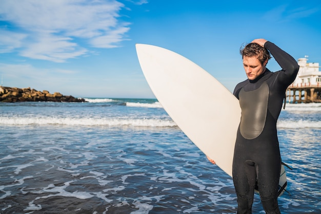 Surfer standing in the ocean with his surfboard