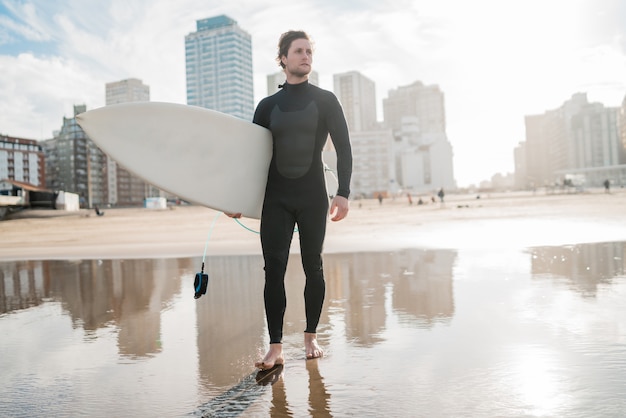 Surfer standing in the ocean with his surfboard.