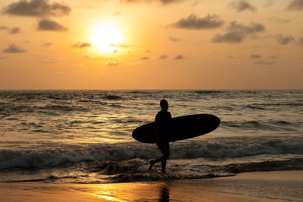 Surfer uit de oceaan bij zonsondergang