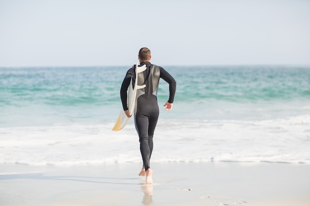 Surfer walking towards sea with a surfboard