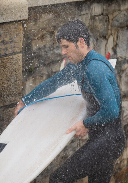 Photo surfer washing surfboard at outdoor beach shower