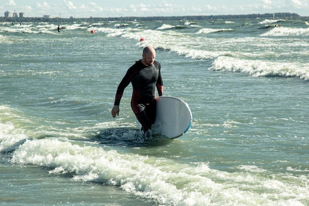 Photo surfer in a wetsuit enters the sea