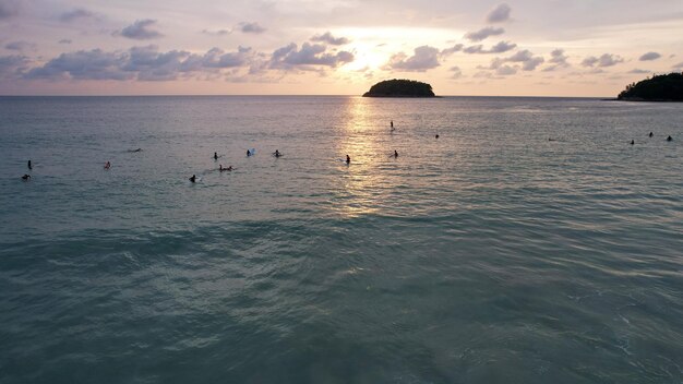 Surfers are waiting for a wave at sunset