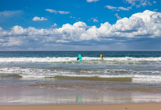 Surfers gaan op een zonnige lentedag op zeegolven surfen