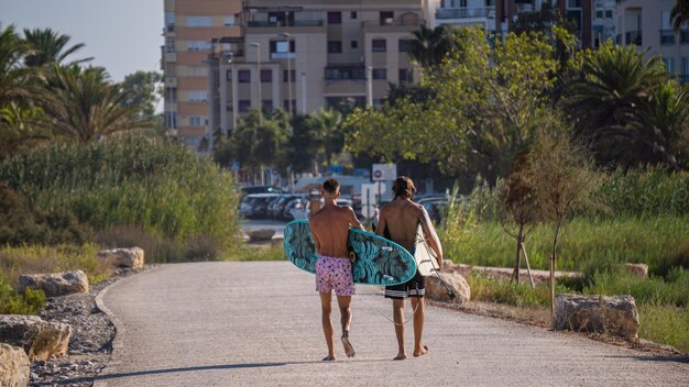 surfers walking along a boardwalk with their surfboards