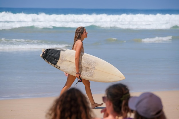 Photo surfgirl walking against the ocean on the beach