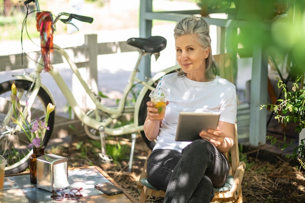 Surfing internet. a woman sitting outside with a talet and\
watching something online