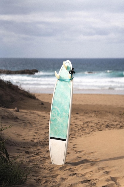 Surfplank in het zand met het strand op de achtergrond