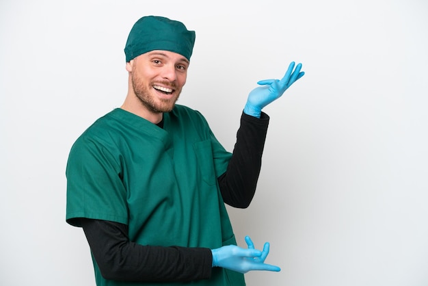 Surgeon Brazilian man in green uniform isolated on white background extending hands to the side for inviting to come