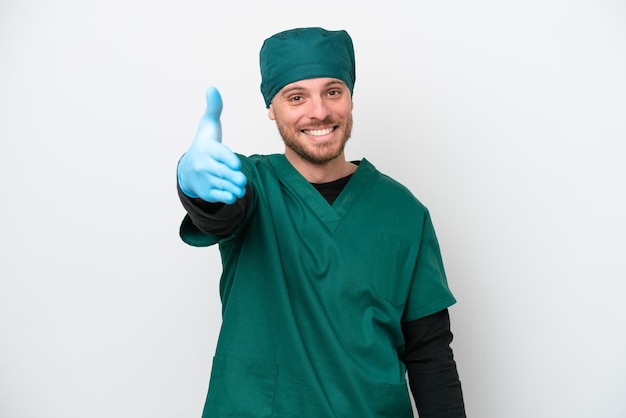 Surgeon Brazilian man in green uniform isolated on white background shaking hands for closing a good deal