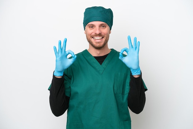 Surgeon Brazilian man in green uniform isolated on white background showing an ok sign with fingers