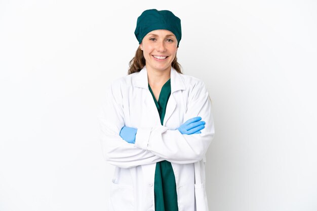 腕を正面の位置で交差させたまま白い背景で隔離の緑の制服を着た外科医白人女性