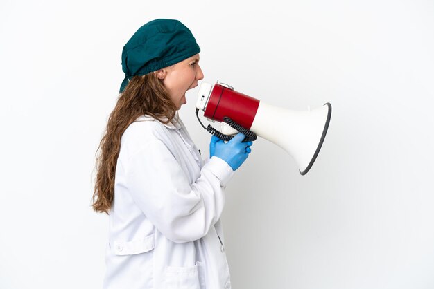 Surgeon caucasian woman in green uniform isolated on white background shouting through a megaphone