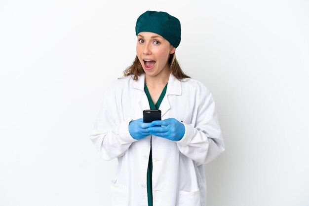 Surgeon caucasian woman in green uniform isolated on white background surprised and sending a message