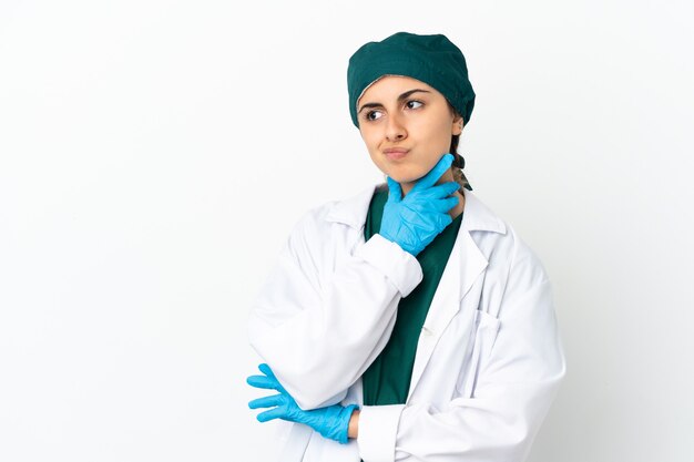 Surgeon caucasian woman isolated on white background having doubts