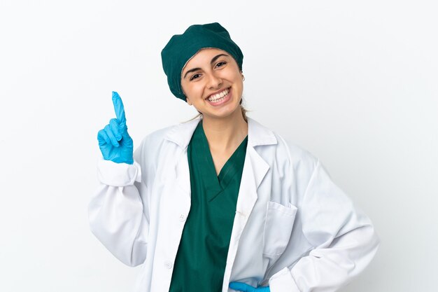 흰색 배경에 격리된 백인 외과의사 여성은 최고의 표시로 손가락을 들고 들어올립니다.
