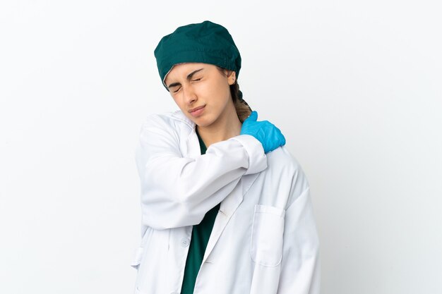 Surgeon caucasian woman isolated on white background suffering from pain in shoulder for having made an effort