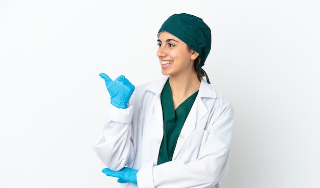 Surgeon caucasian woman isolated on white wall pointing to the side to present a product