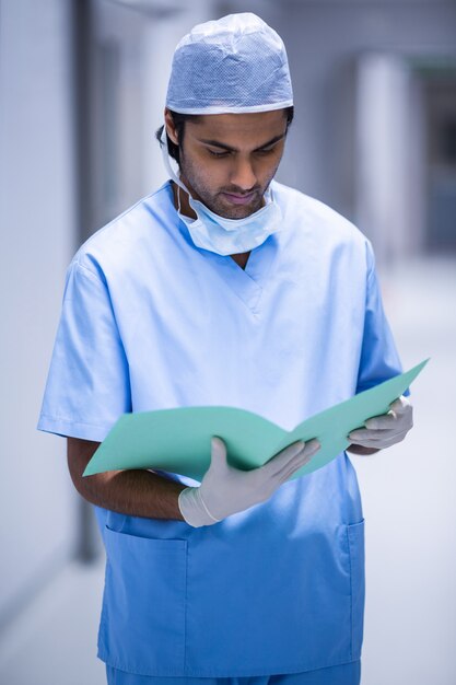 Surgeon checking report in corridor