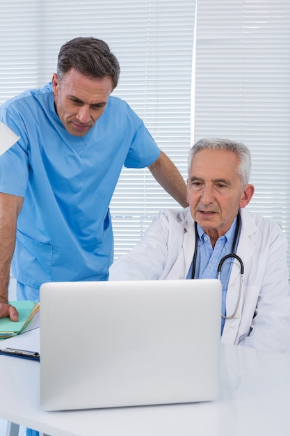 Surgeon and doctor discussing over laptop